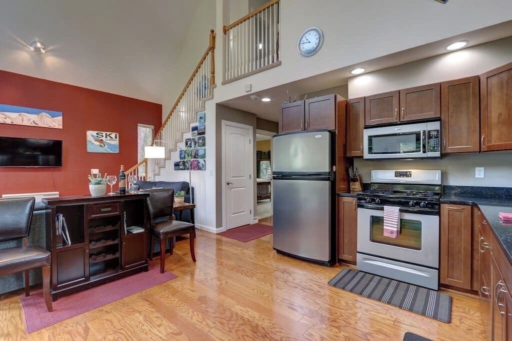 A kitchen with wooden cabinets, a stainless steel refrigerator, a microwave, and an oven.