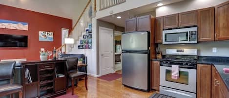 A kitchen with wooden cabinets, a stainless steel refrigerator, a microwave, and an oven.