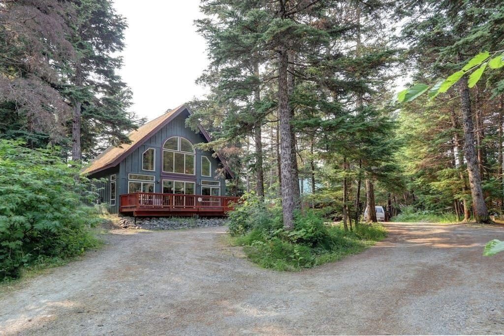 A cabin with a porch, surrounded by dense forest.