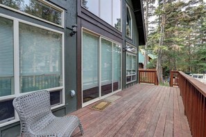 A wooden deck with a chair, large windows, and a view of trees. - Girdwood Lodge w/ Sauna, Near Alyeska Resort (Girdwood)