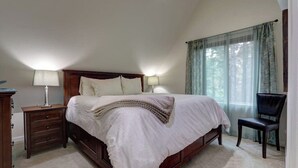 A bedroom with a large bed, two bedside tables with lamps, a chair, and a window with curtains. - Girdwood Lodge w/ Sauna, Near Alyeska Resort (Girdwood)