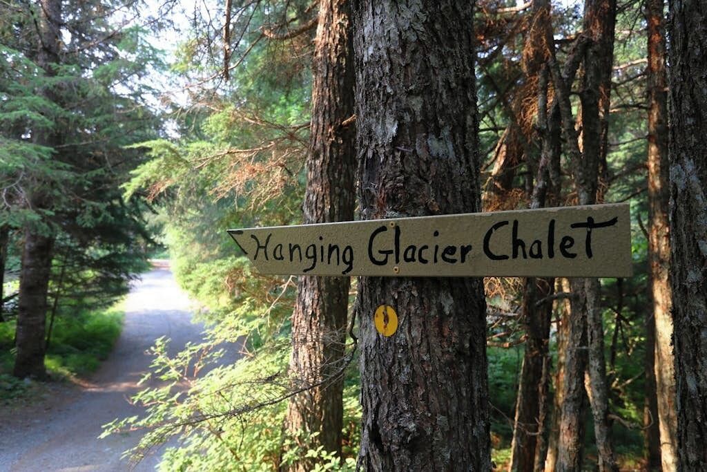 A signpost in a forested area with a path leading through it.
