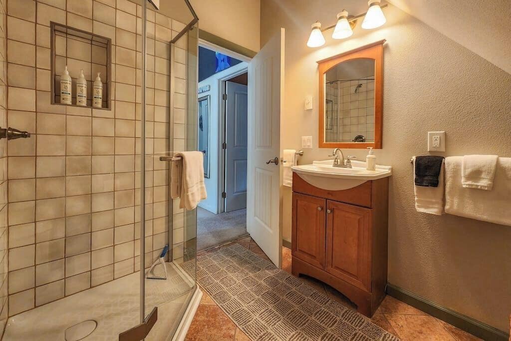 A bathroom with a shower, sink, mirror, and towel rack.