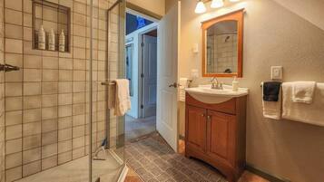 A bathroom with a shower, sink, mirror, and towel rack.