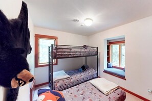 A room with bunk beds, a window seat, and a stuffed toy.