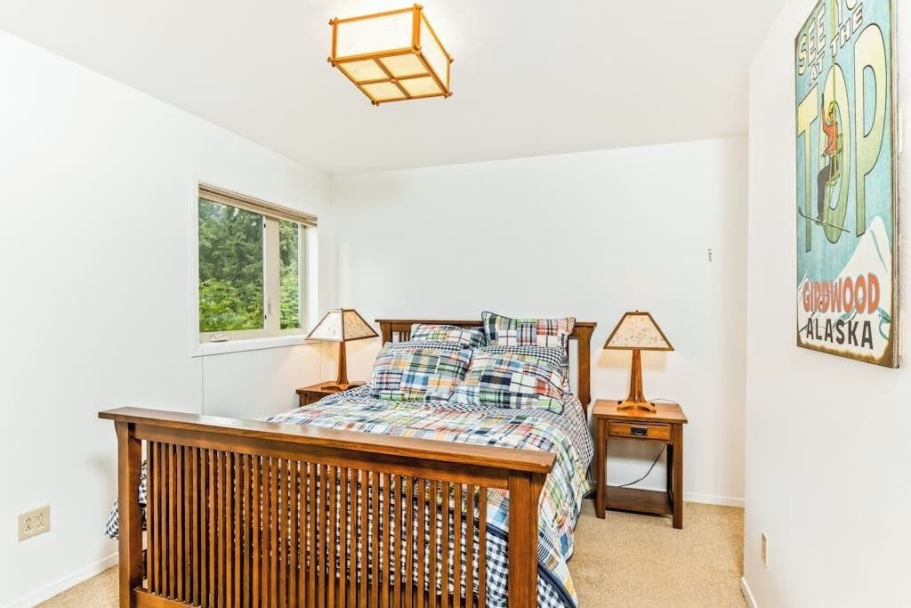 A bedroom with a wooden bed, two bedside tables, a window, and a wall poster.