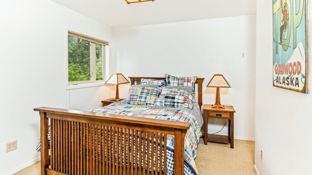 Un dormitorio con cama de madera, dos mesitas de noche, un ventanal y un cartel en la pared.
