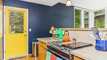 A kitchen with a stove, oven, and a yellow door.