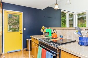 Una cocina con estufa, horno y una puerta amarilla.