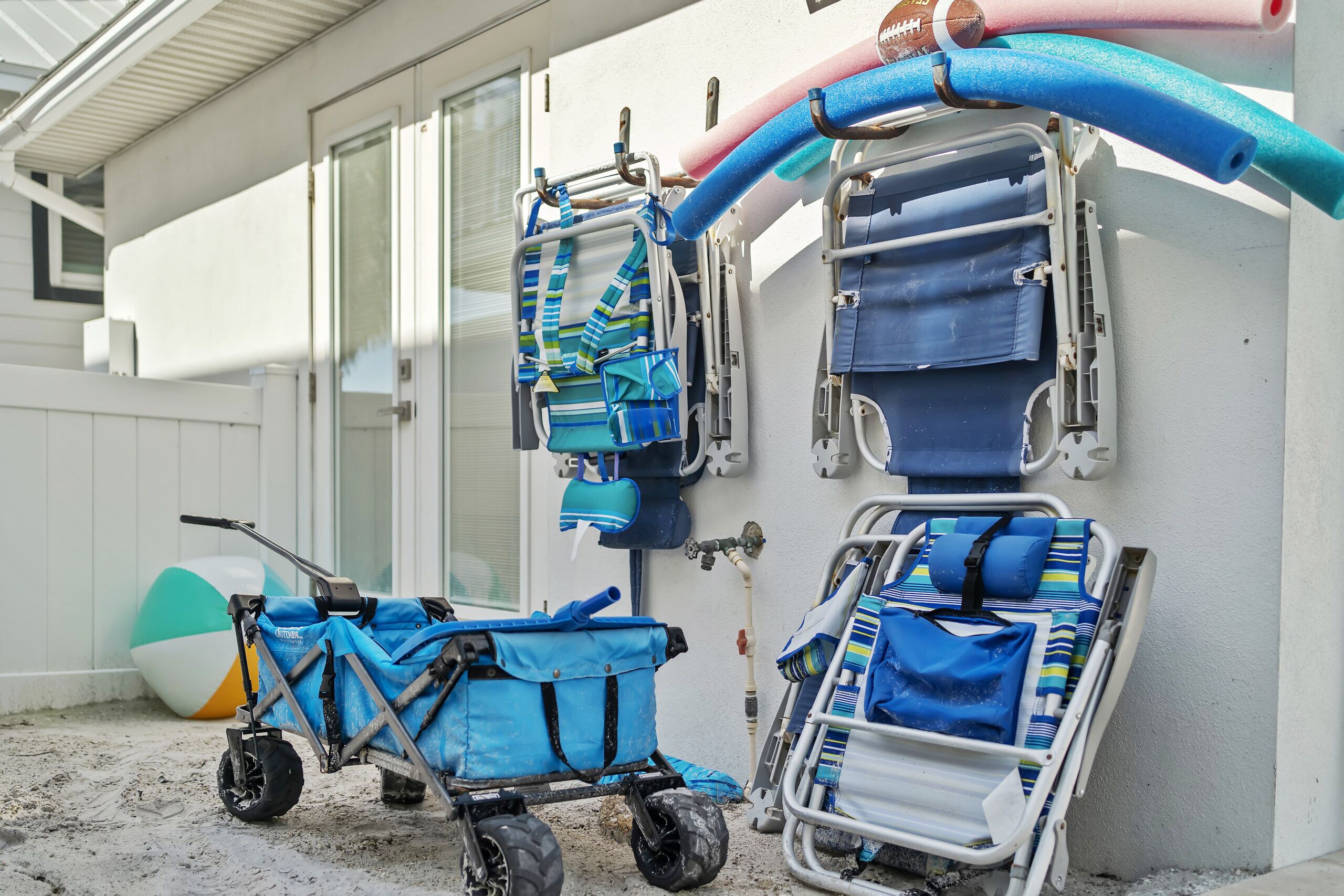 A beachside setting with a beach chair, a beach umbrella, and a blue beach cart.