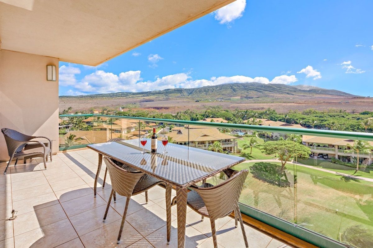 Ein Balkon mit Tisch und Stühlen, mit Blick auf eine Landschaft aus Gebäuden und Hügeln.