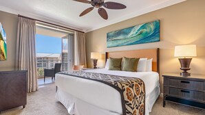 A hotel room with a bed, two bedside lamps, a ceiling fan, a painting, and a view of the ocean. - Honua Kai Resort & Spa by Maui Resort Rentals (Kaanapali)