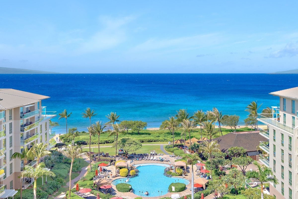 Ein Resort mit einem zentral gelegenen Pool, Palmen und Blick auf das Meer.