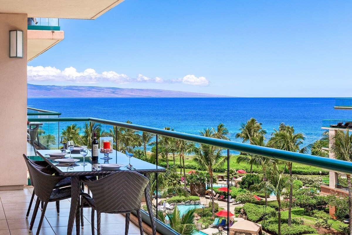 Ein Balkon mit Esstisch, der auf einen Pool und einen tropischen Garten blickt.