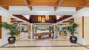 A spacious lobby with a wooden boat centerpiece, large potted plants, and a modern chandelier. - Honua Kai Resort & Spa by Maui Resort Rentals (Kaanapali)