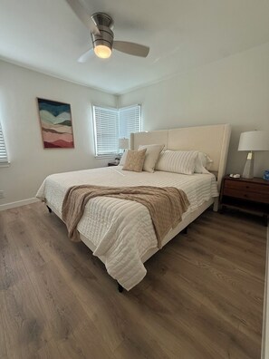 A bedroom with a bed, a nightstand, a lamp, a ceiling fan, and a painting on the wall. - Elegantly Renovated Burbank Retreat! (Burbank)