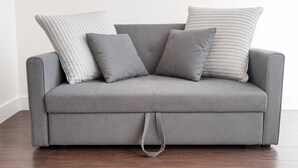 A grey sofa with a matching throw pillow and a grey cushion. - Modern 1BR Flat Sleeps 5 in Wimbledon (London)