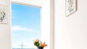 A dining area with a table and chairs, a vase with flowers, and a view of the city through a large window. - Modern 1BR Flat Sleeps 5 in Wimbledon (London)