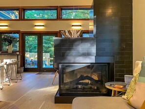 Ein modernes Wohnzimmer mit Kamin, Essbereich und großen Fenstern.