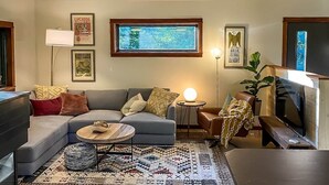 A living room with a sofa, coffee table, lamp, and television. - The Retreat at Fox Lake (Athens Township)
