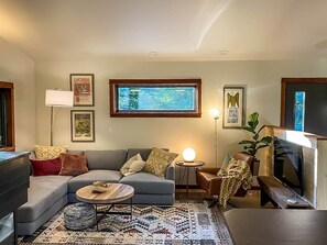 Ein Wohnzimmer mit Sofa, Couchtisch, Lampe und Fernseher.
