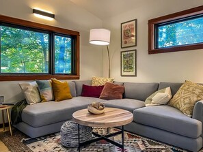 Un salon moderne avec un canapé gris, une table basse ronde et un lampadaire.