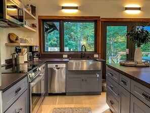 Une cuisine moderne dotée d’appareils électroménagers en acier inoxydable, de meubles en bois et d’une grande fenêtre offrant une vue sur l’extérieur.