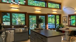 A modern kitchen with a central island, built-in appliances, and large windows offering a view of the outdoors. - The Retreat at Fox Lake (Athens Township)