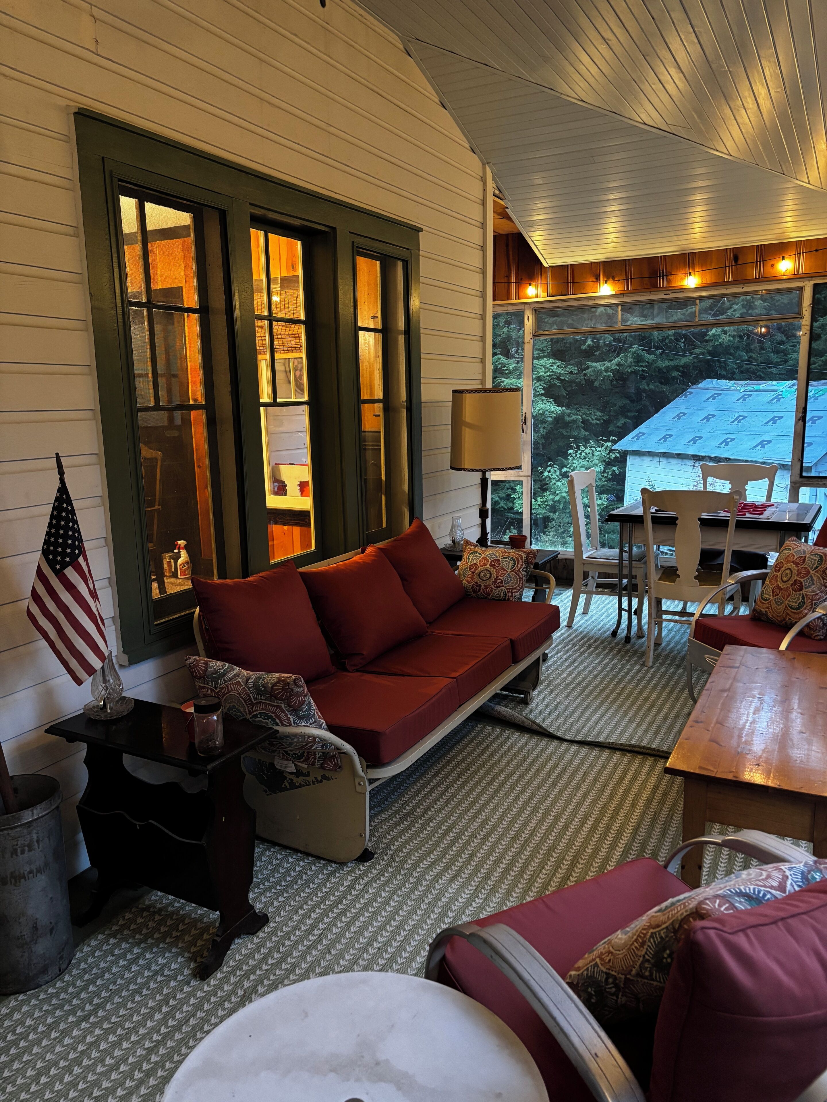A cozy room with a red sofa, a small table, and a view of a house through a window.