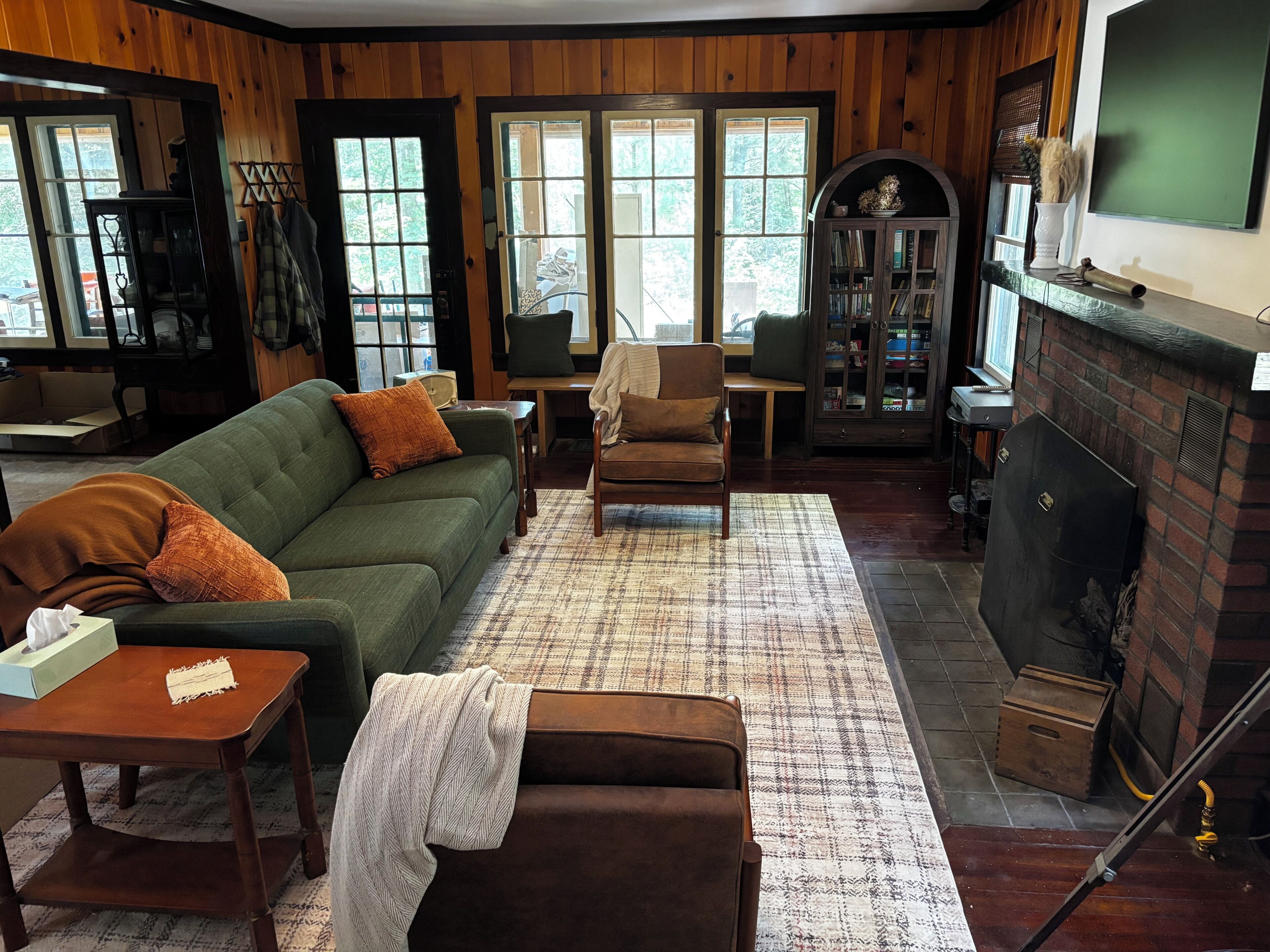 Una sala de estar acogedora con un sofá verde, un sillón marrón y una chimenea.