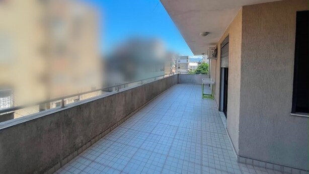 A corridor with tiled flooring, a concrete wall, and a building entrance with a door. - Modern apartment (Shkodër)