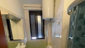A bathroom with two sinks, a toilet, a bidet, a window with blinds, and a shower area. - Modern apartment (Shkodër)