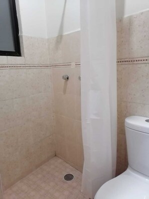 Ein Badezimmer mit Dusche, Toilette und Spiegel.