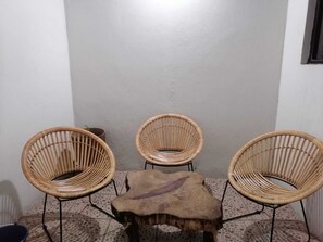 Eine Sitzecke mit drei Korbstühlen und einem kleinen Holztisch.