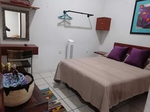 Ein Schlafzimmer mit einem Bett, einem Nachttisch, einem Spiegel, einer Wandheizung, einer Pendelleuchte und einem gerahmten Bild.