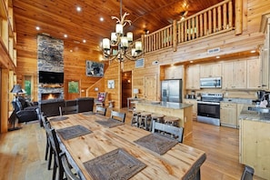 A spacious wooden cabin interior with a dining area, kitchen, and a fireplace. - High Smokies Lodge: Game Room, Hot Tub, Pet-Friendly (Sevierville)