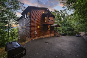 A log cabin with a staircase leading to a porch, surrounded by trees. - High Smokies Lodge: Game Room, Hot Tub, Pet-Friendly (Sevierville)