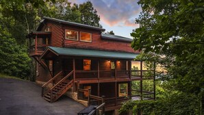 A two-story log cabin with a balcony, a staircase, and a porch. - High Smokies Lodge - Game Room, Hot Tub and more! (Sevierville)
