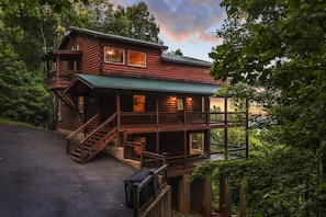 A two-story log cabin with a balcony, a staircase, and a porch. - High Smokies Lodge - Game Room, Hot Tub and more! (Sevierville)
