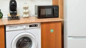 A compact kitchen with a washing machine, microwave, and a refrigerator. - Church View by Stayguest (Santa Cruz)