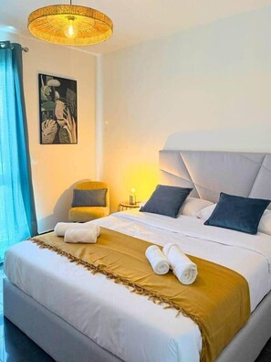 A hotel room with a large bed, a bedside table, a chair, and a wall-mounted artwork. - Church View by Stayguest (Santa Cruz)