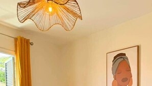 A hotel room with a bed, a chair, a lamp, a painting, and a window with curtains. - Church View by Stayguest (Santa Cruz)