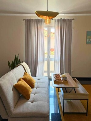 A living room with a sofa, a coffee table, and a hanging light fixture. - Church View by Stayguest (Santa Cruz)