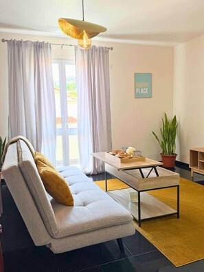 A modern living room with a sofa, coffee table, and a hanging light fixture. - Church View by Stayguest (Santa Cruz)