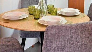 A dining area with a round table, chairs, a vase with flowers, and a small cabinet. - Church View by Stayguest (Santa Cruz)