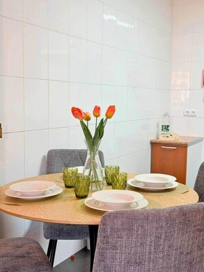 Ein Essbereich mit einem runden Tisch, Stühlen, einer Blumenvase und einem kleinen Schrank.