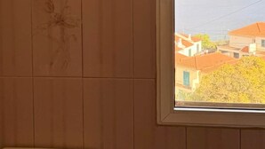 Et badeværelse med toilet, et vindue og udsigt til bygninger.