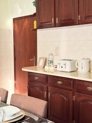 A kitchen with wooden cabinets, a countertop, a toaster, a kettle, and a framed certificate. - Recanto da Bemposta by Stayguest (Machico)