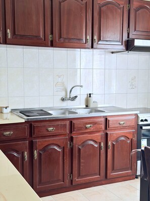 A kitchen with wooden cabinets, a stainless steel sink, and a built-in oven. - Recanto da Bemposta by Stayguest (Machico)