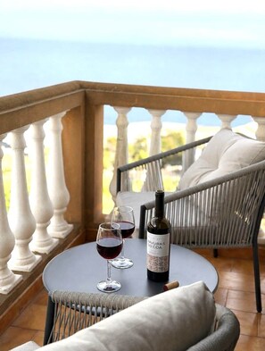 A balcony with a round table, two wine glasses, and a bottle of wine. - Recanto da Bemposta by Stayguest (Machico)